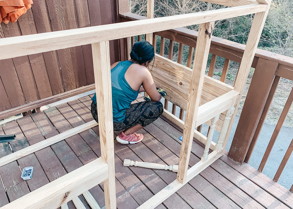 Shot of Ashleigh attaching wood to the sides of the playhouse