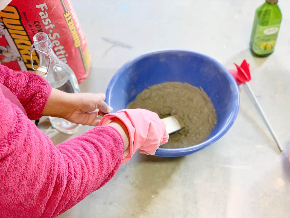 Ashleigh mixing concrete in bowl with stir stick