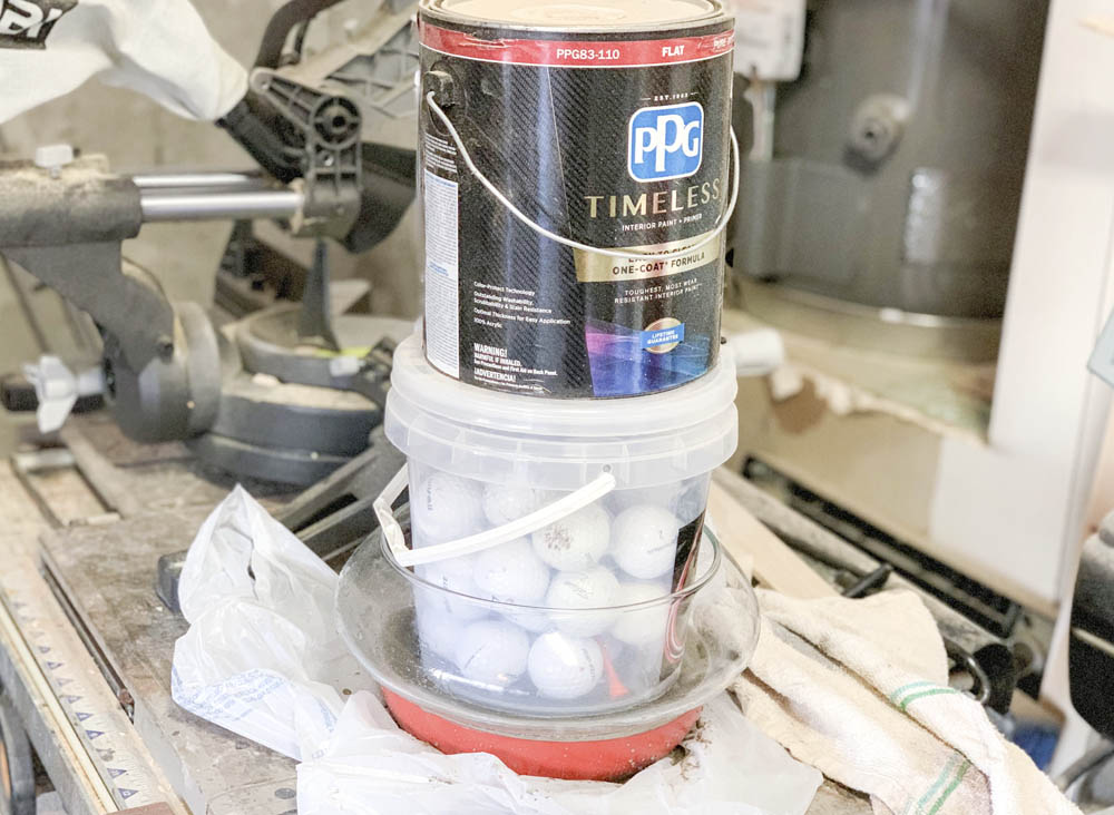 A can of paint and a bucket of golf balls inside a bowl to help concrete set