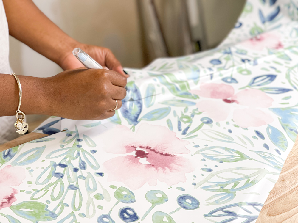 A woman using a knife to cut floral wallpaper A woman using a knife to cut floral wallpaper