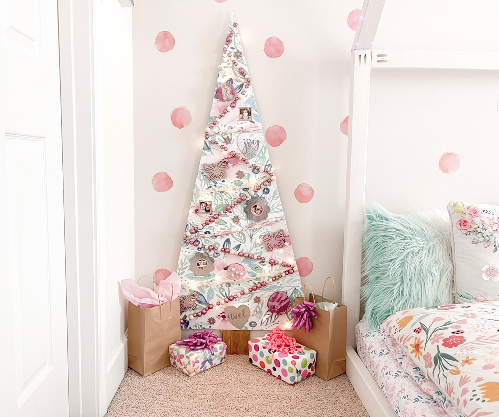 A finished DIY Scandanavian Wooden Tree against a polka-dot wall with presents on the ground A finished DIY Scandanavian Wooden Tree against a polka-dot wall with presents on the ground