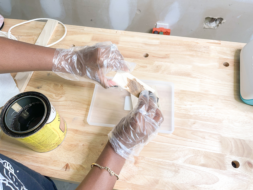 Hands with plastic gloves applying stain to small pieces of wood Hands with plastic gloves applying stain to small pieces of wood