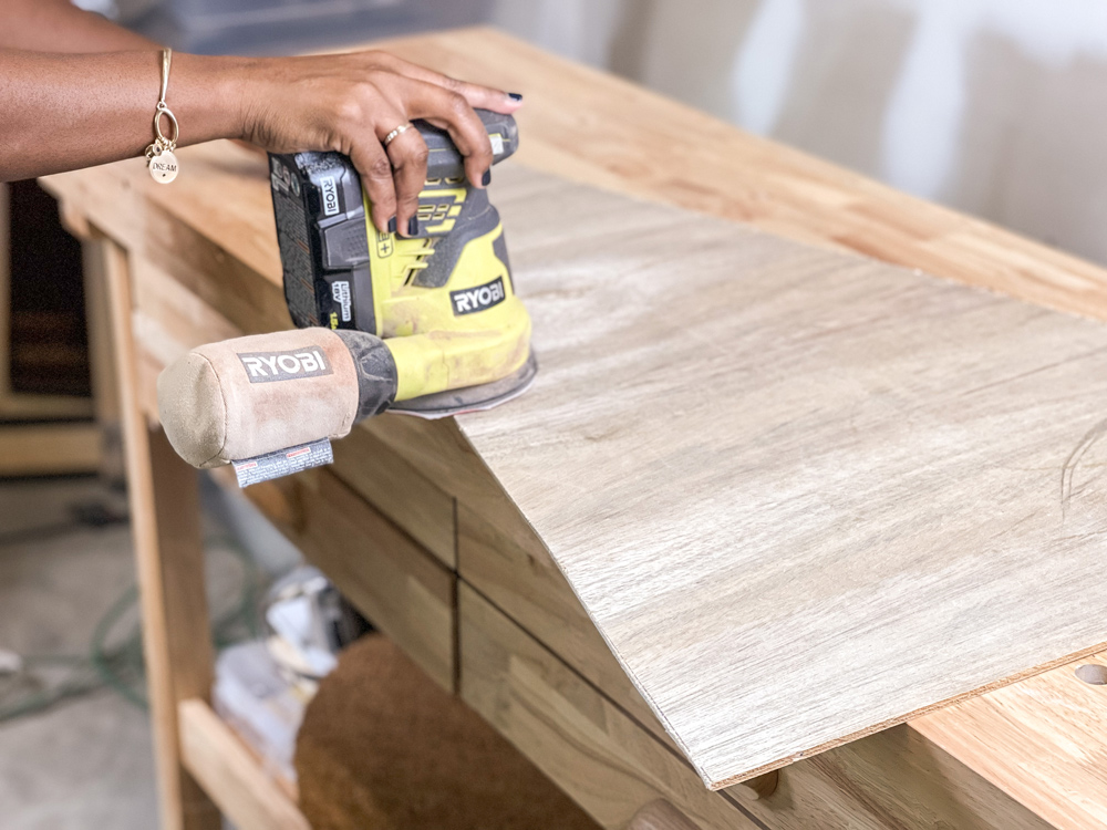 Hands using an orbital sander on a piece of cut plywood Hands using an orbital sander on a piece of cut plywood