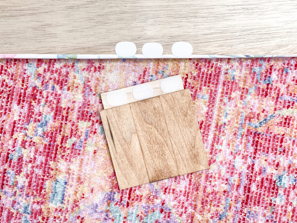 Stained pieces of wood next to a piece of plywood with velcro pieces attached Stained pieces of wood next to a piece of plywood with velcro pieces attached