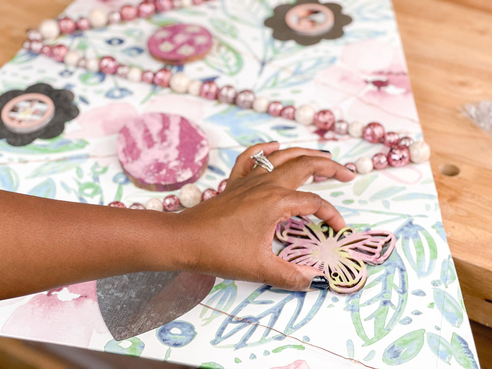 A hand placing a diy wooden butterfly ornament onto a DIY Scandanavian Wooden Tree A hand placing a diy wooden butterfly ornament onto a DIY Scandanavian Wooden Tree