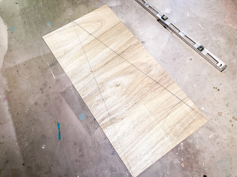 A level and a piece of plywood on the ground with a triangular shape drawn A level and a piece of plywood on the ground with a triangular shape drawn