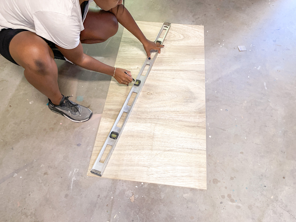A woman measuring plywood using a level on the ground A woman measuring plywood using a level on the ground