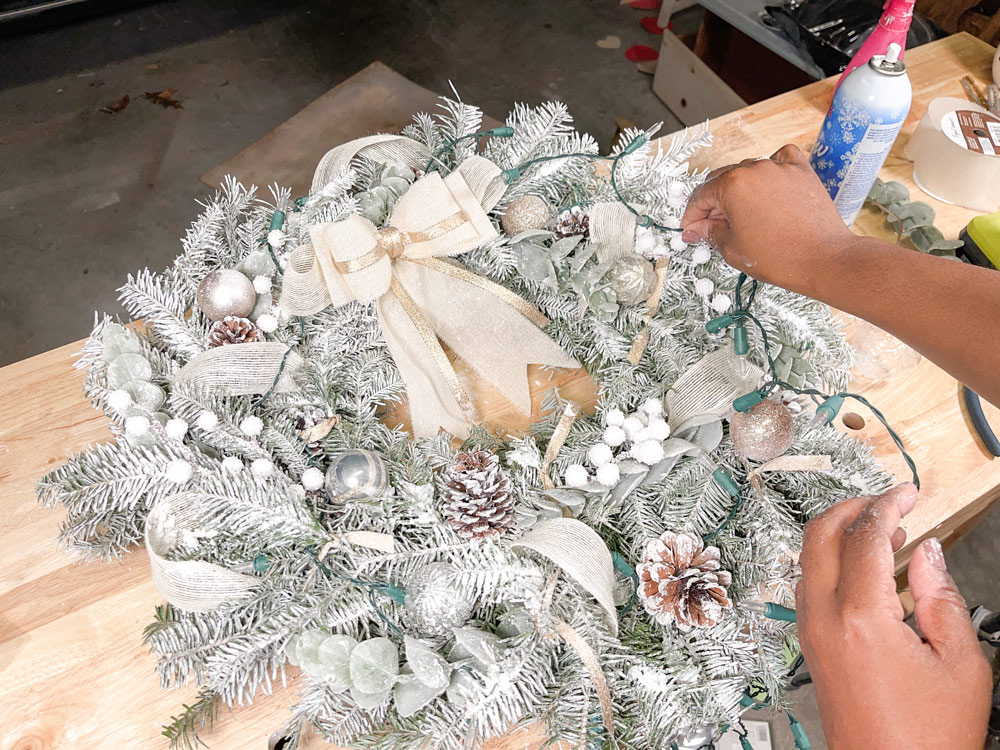 Hands applying LED lights to a DIY Flocked Wreath.