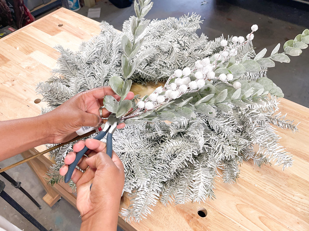 Hands holding pieces of eucalyptus and cutting stems with pliers.