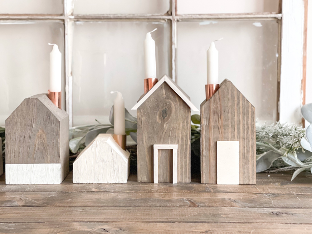 Four DIY Wooden House Candle Holders sitting in front of a window pane