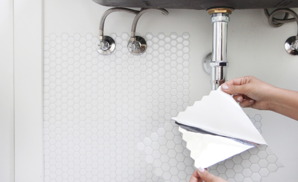 A person applies adhesive tile in a bathroom. A person applies adhesive tile in a bathroom.