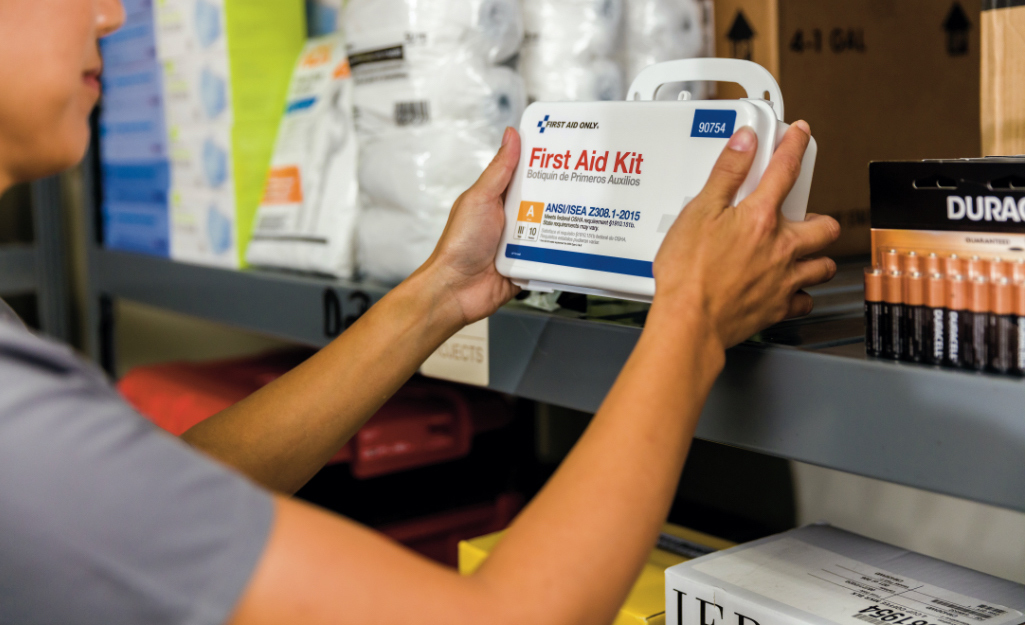 A person removes a first aid kit from a shelf.