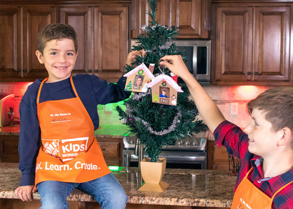 Boys with a Christmas tree decorated with DIY house ornaments.