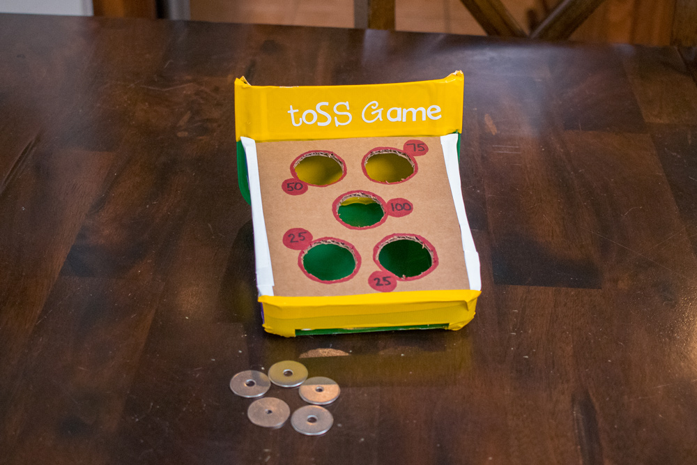 A finished DIY toss game and metal washers on a table.