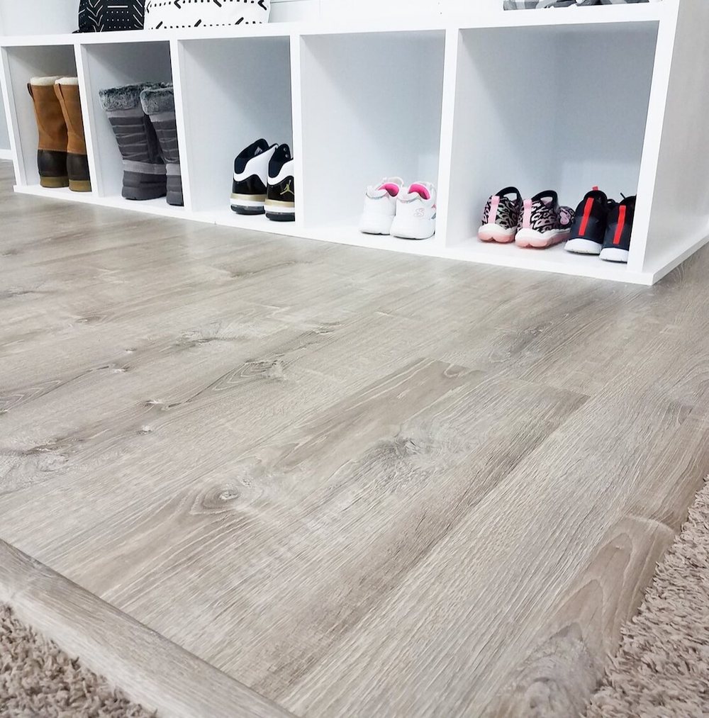 Close up of wooden flooring and shoes placed in white cupboard holes 