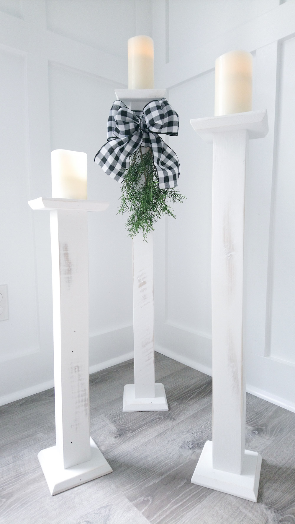 Three LED Light candles sitting on DIY floor candle sticks with a black and white bow in the center