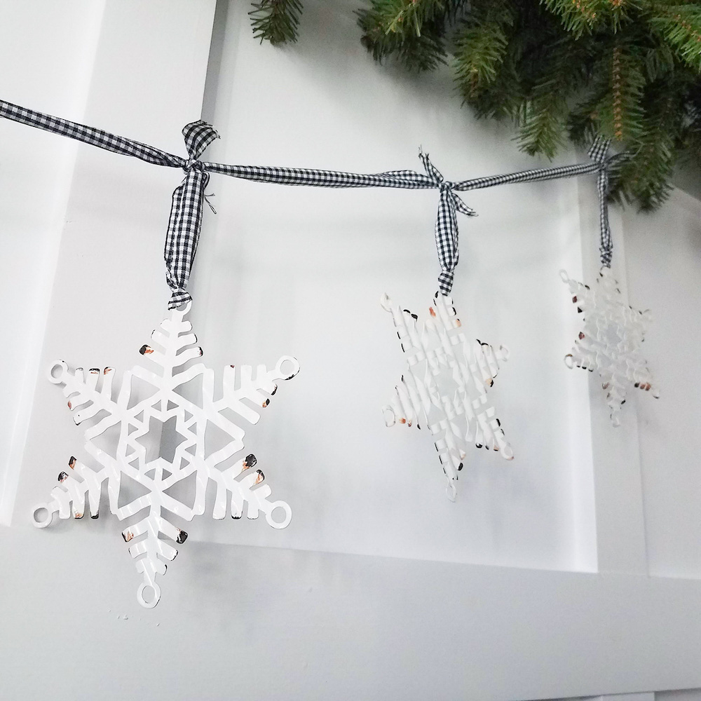 Close up a faux snowflakes hanging by black and white ribbon on a wall