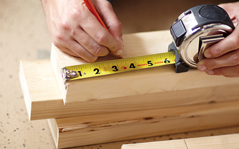 A person marking wood with a tape measure.