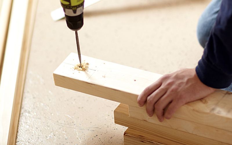 A person drilling holes for the legs of the table.
