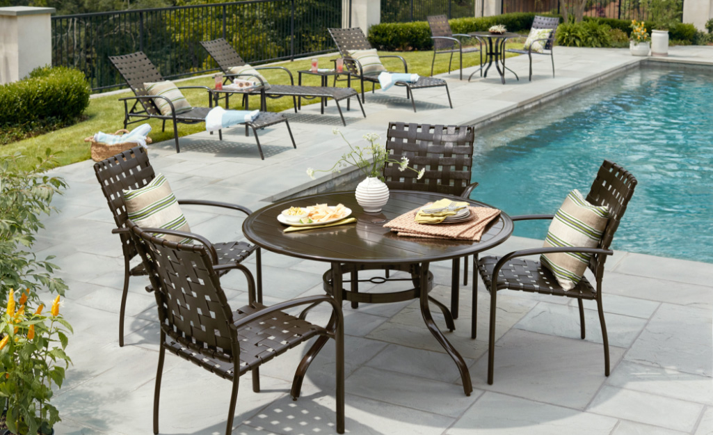 Outdoor furniture stands on a poolside patio.