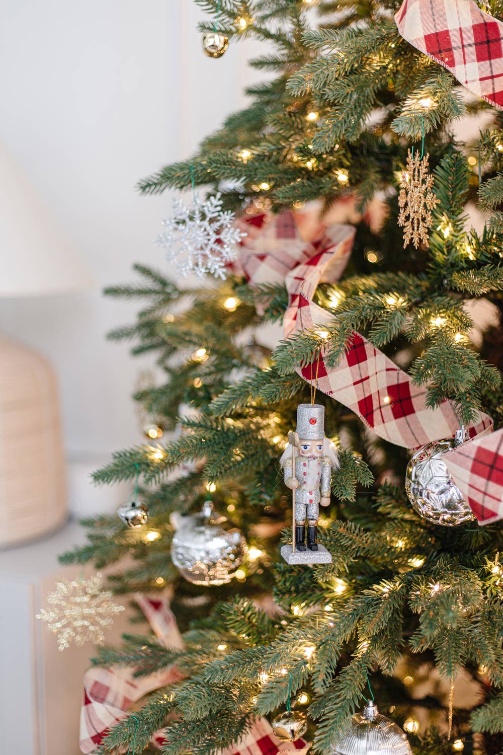 Close-up shot of a traditional tree with plaid ribbon and silver nutcracker ornaments.