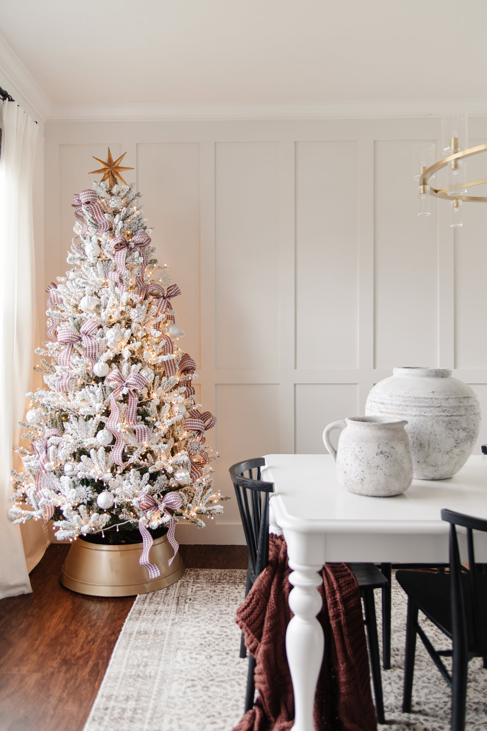 Corner of dining room featuring a white table and frocked Christmas tree. 