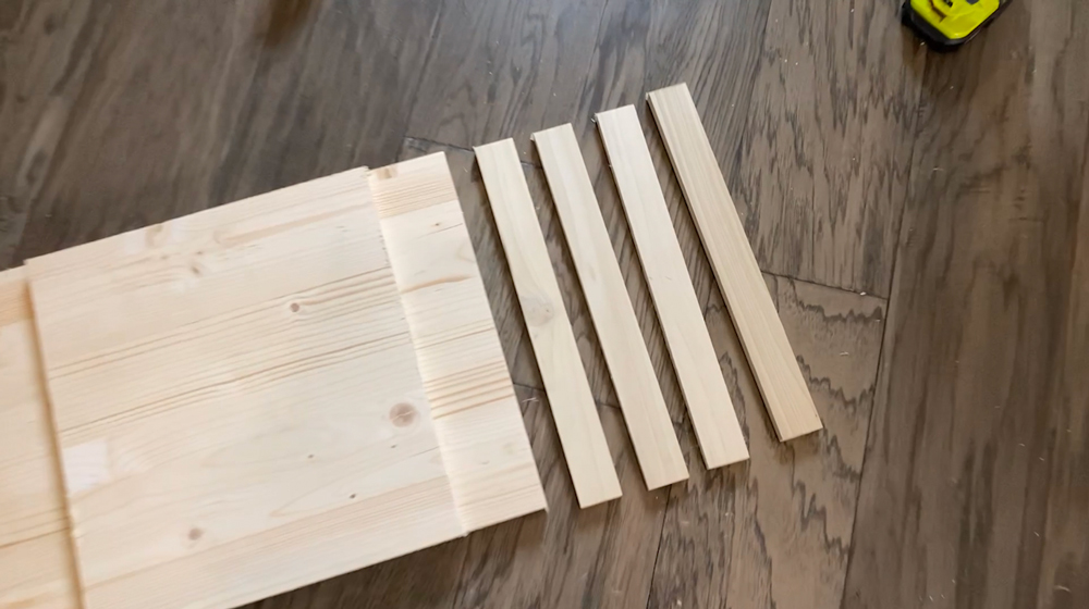 A large board of wood next to four cut pieces of wood