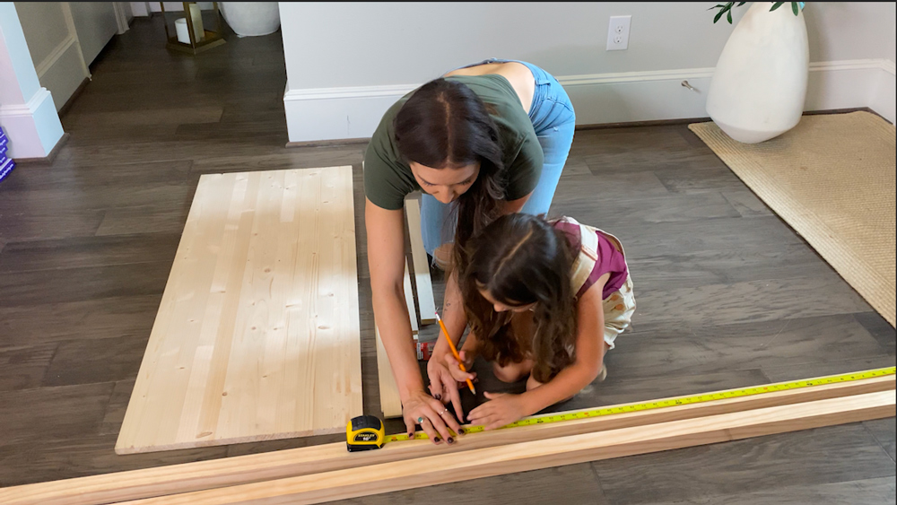 A woman and a child measuring wooden boards with a measuring tape