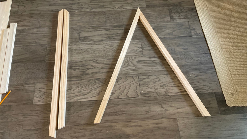 Four pieces of wood on the ground with two of them set up in a triangular shape