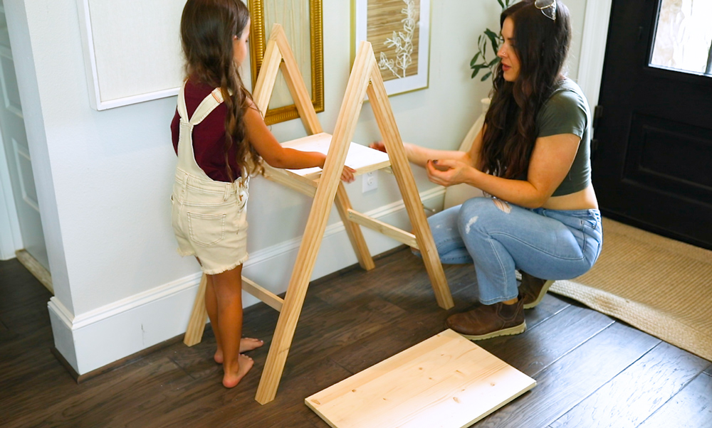 A child and a woman adding a shelf to a DIY present ladder