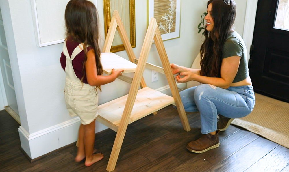 A child and a woman adding a top shelf to a DIY present ladder