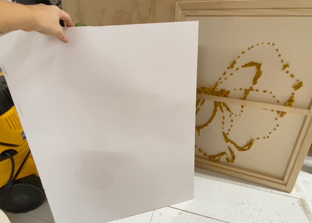 Person holding piece of whiteboard up to wood frame.