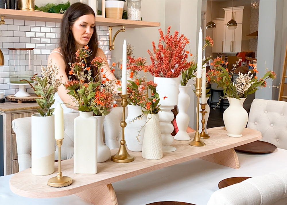 Person arranging faux flowers in painted vases on the graze board. 