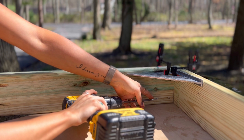 A woman drilling into a pocket hold on a board of wood.