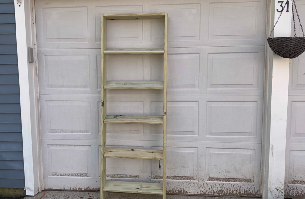 A wooden bookcase frame resting on a garage door.