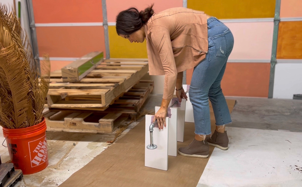 A woman holding a DIY plant shelf upright.