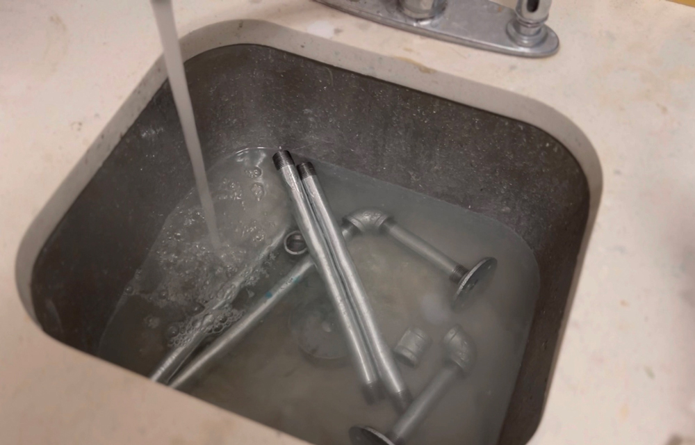 Metal pipes in a sink with water running.