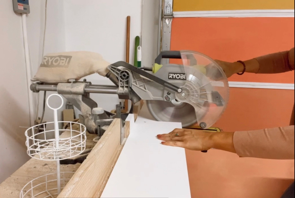 A woman’s hands holding a board while using a circular saw to cut.