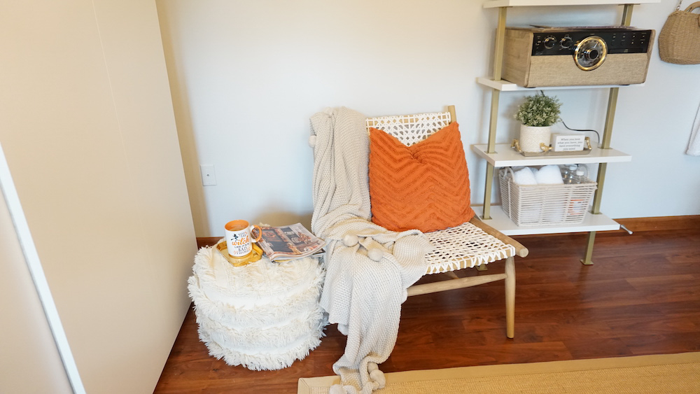 A close shot of the side chair and table with a blanket and pillow used as decor