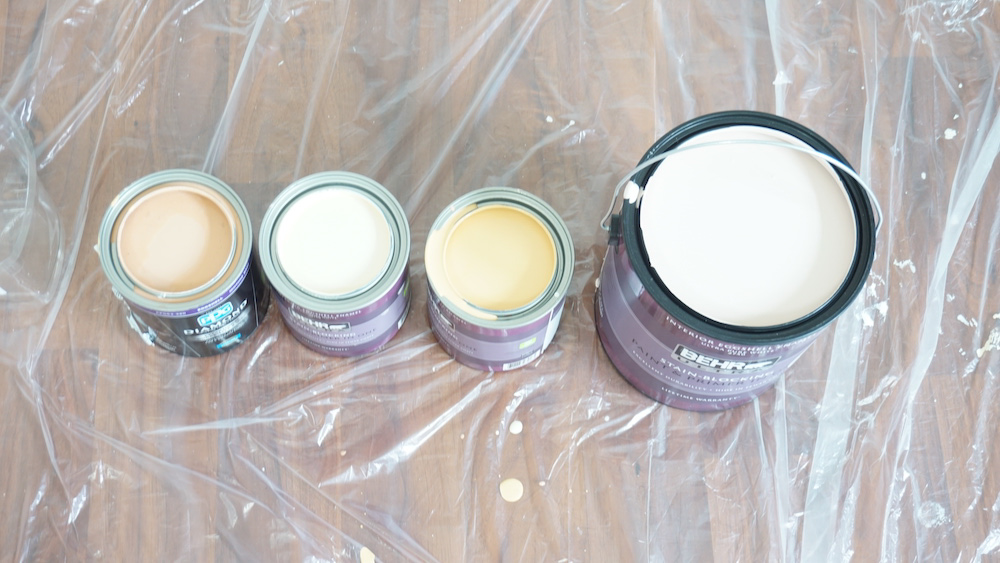 Open lid paint cans on plastic floor cover
