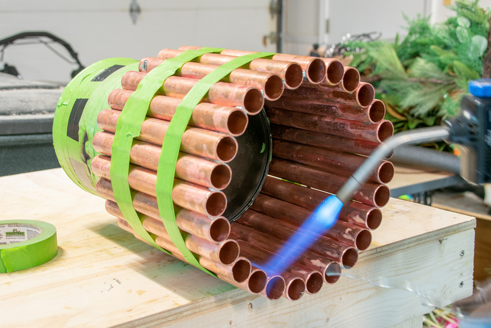 A blow torch being used on a DIY Copper and Wooden planter base.