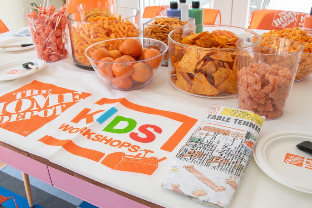 Orange snacks in vases on a table with a Home Depot Celebration Kit craft setup.
