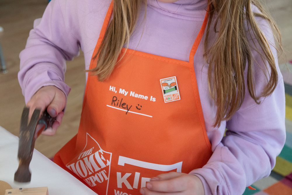 A girl with a Home Depot kid’s apron on with her name written on it.