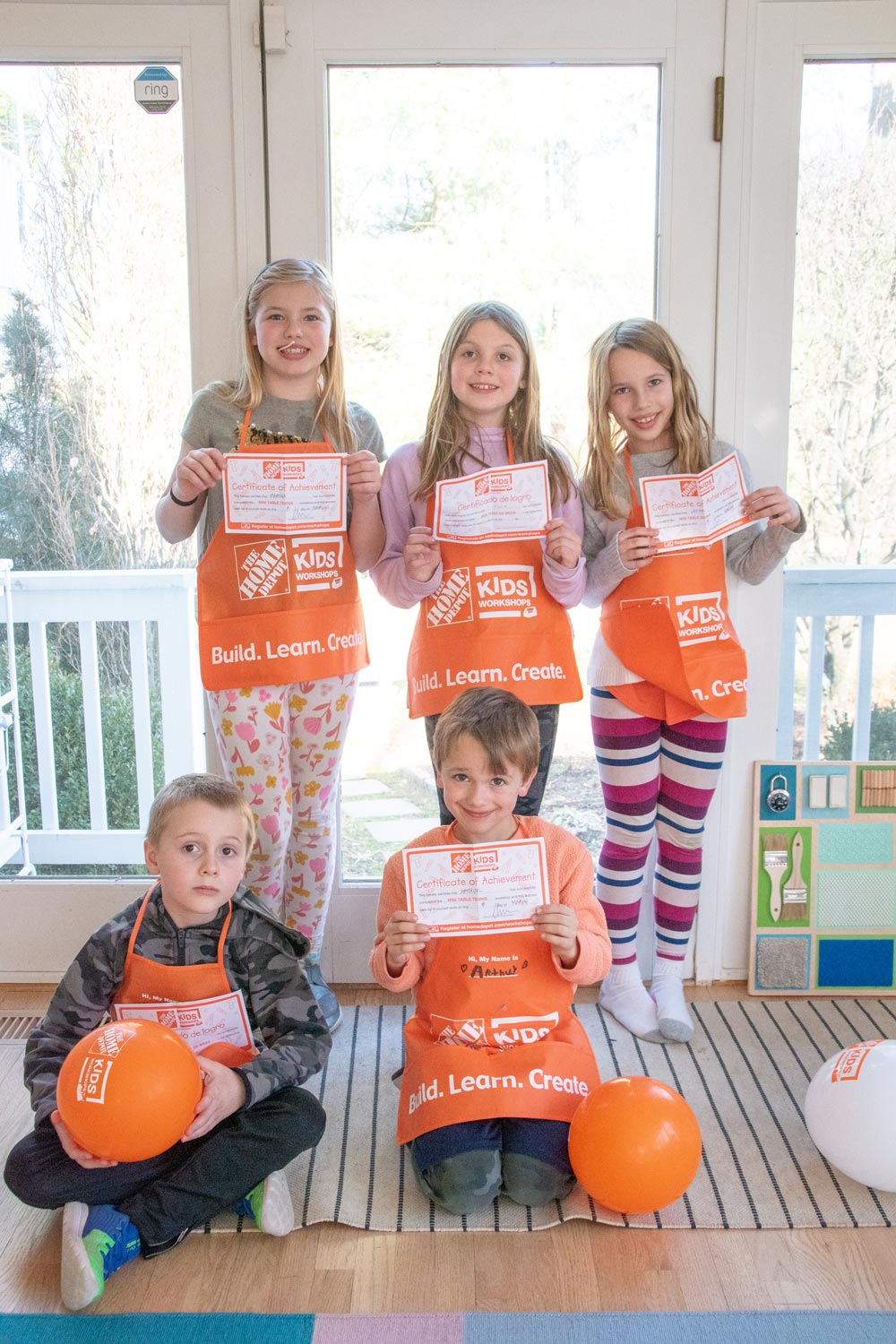 Children with Home Depot kids aprons on holding up certificates of achievement.