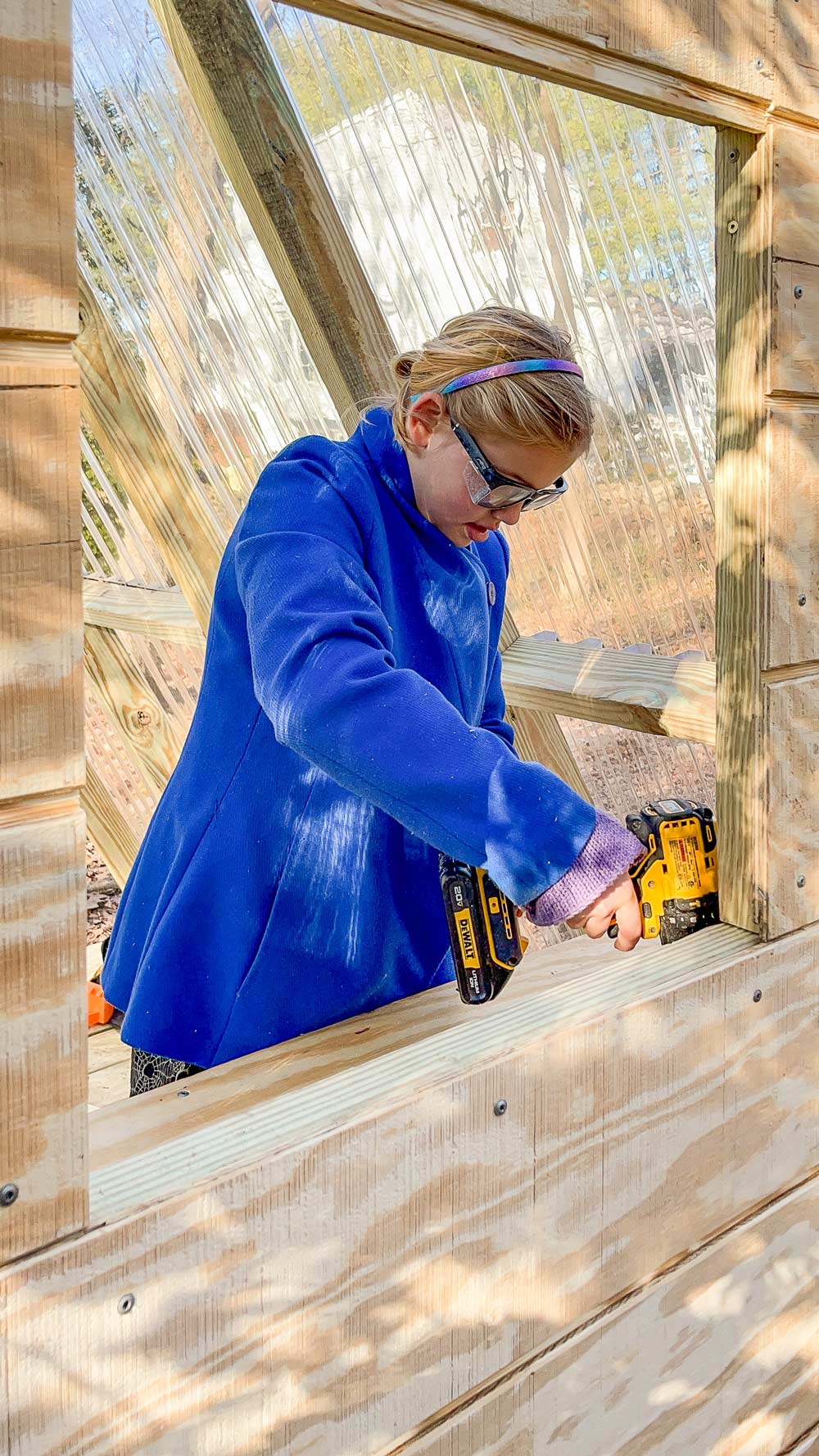 Woman in a blue jacket using a power tool.