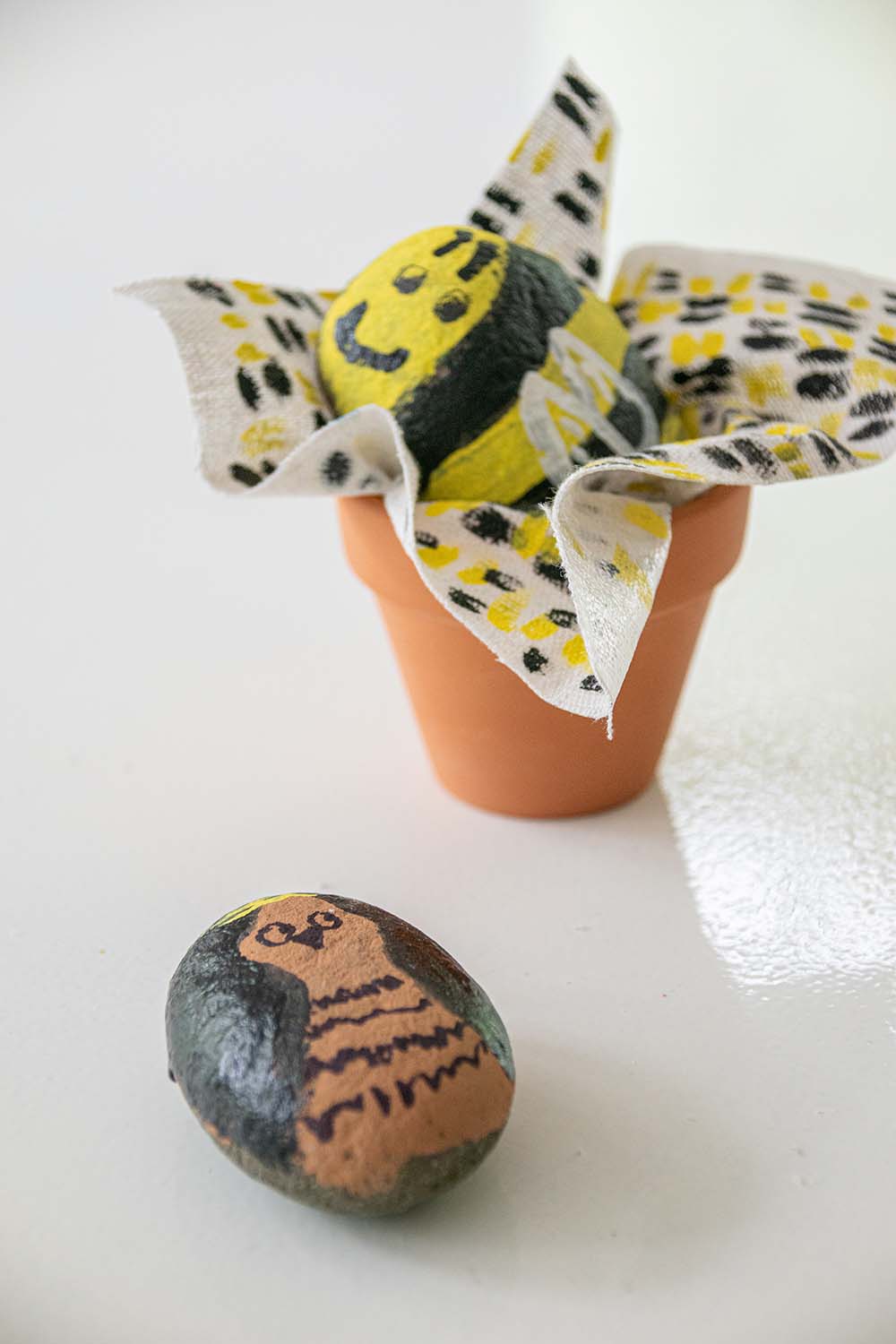 Two painted rocks and a decorated terracotta pot.