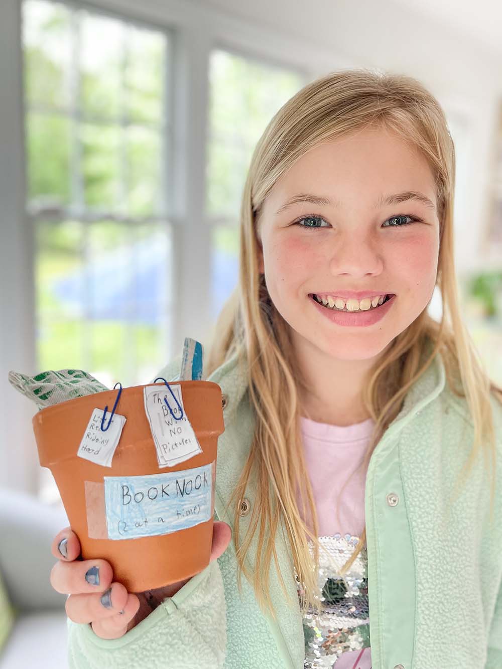 A child with a decorated terracotta flower pot and pillow.