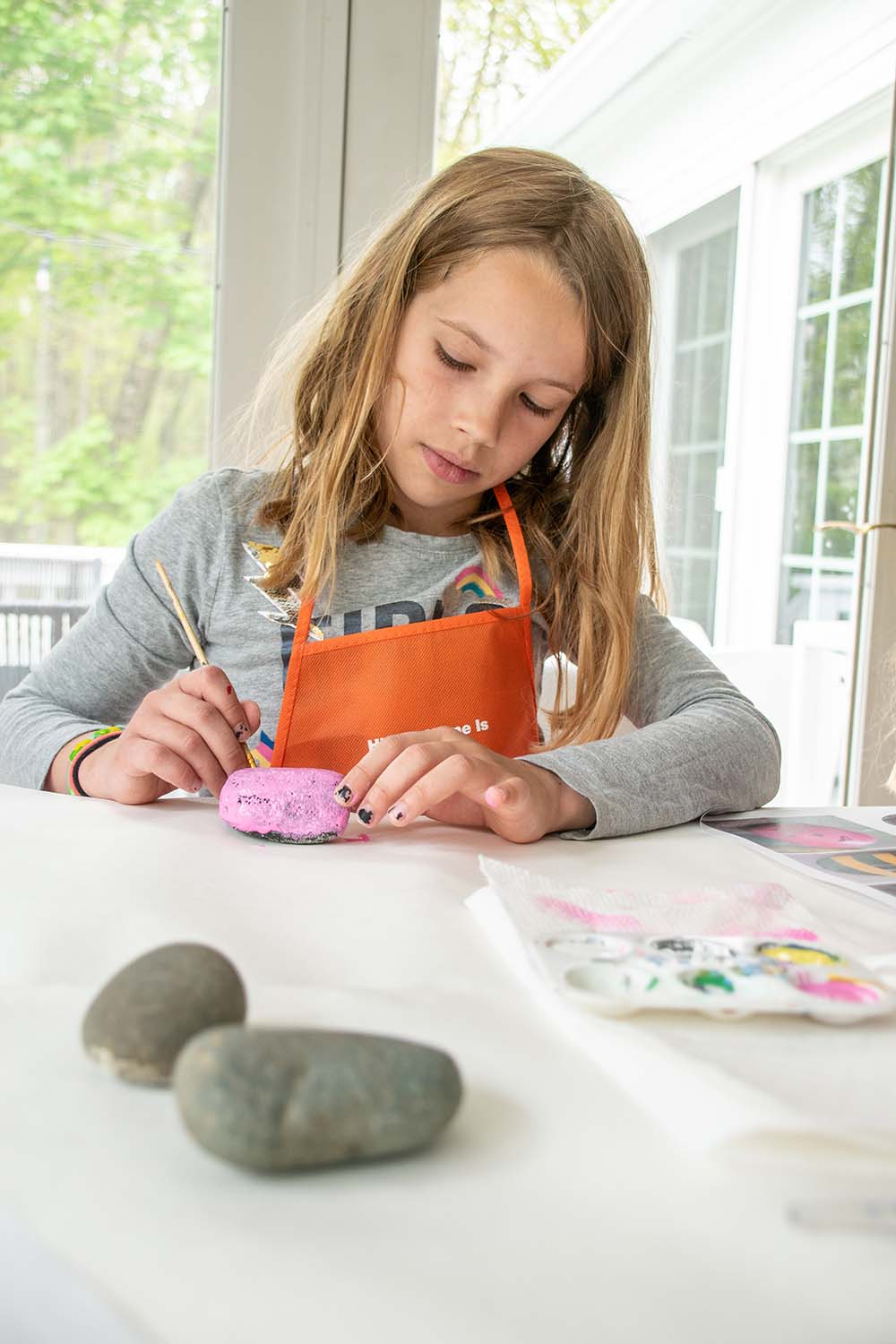 A child painting a rock bright pink.