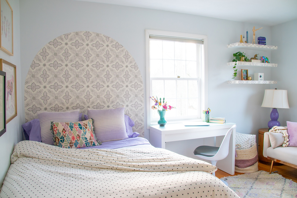Kid’s bedroom with wallpaper headboard, desk, floating shelves, and loveseat.