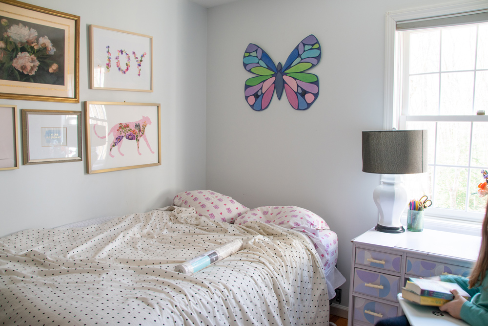 Bedroom with photo frames and a butterfly on the wall.